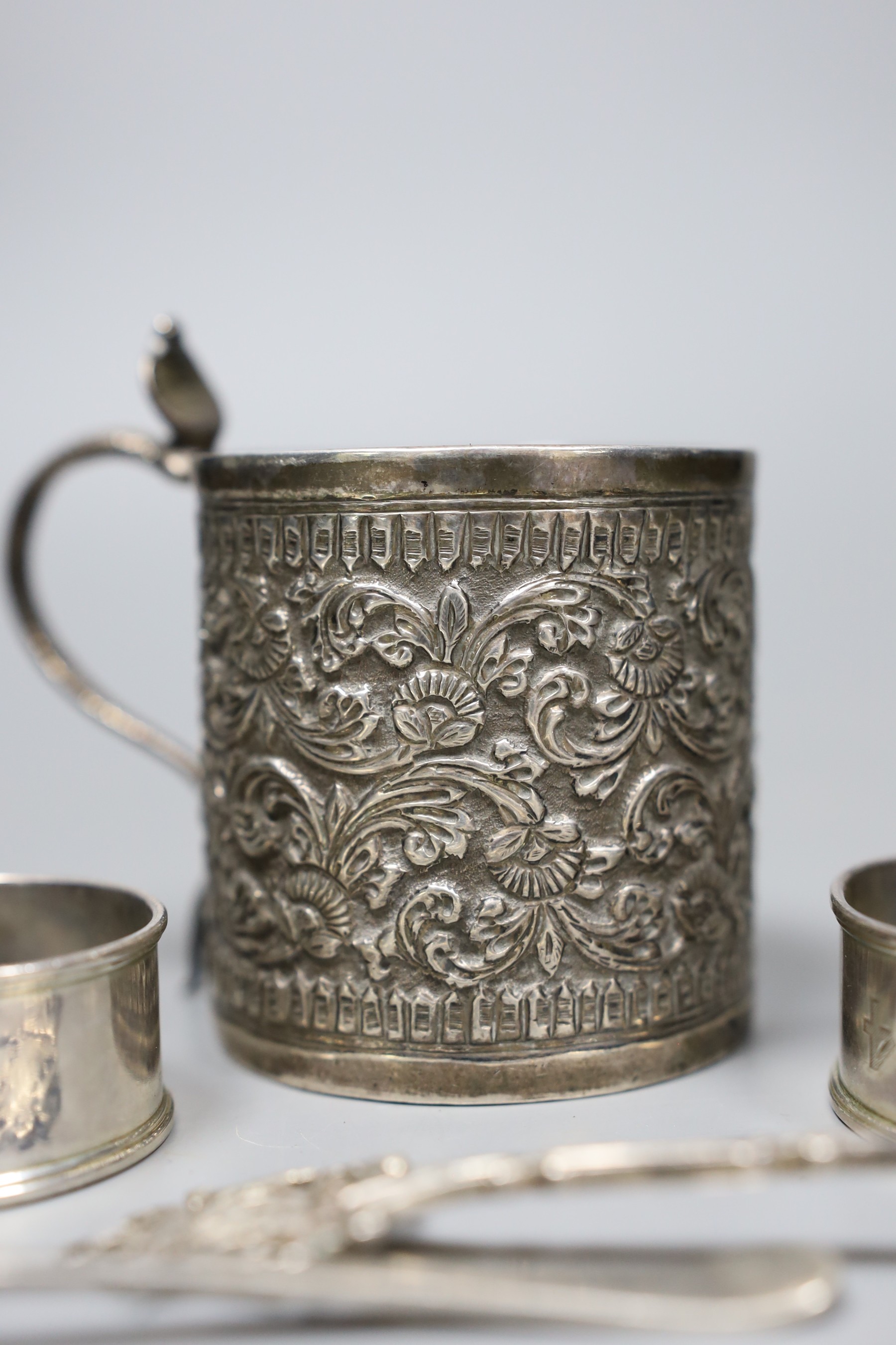 A 19th century Indian white metal christening can with cobra handle, a set of four silver napkin rings, two spoons and three mother of pearl handled butter knives.